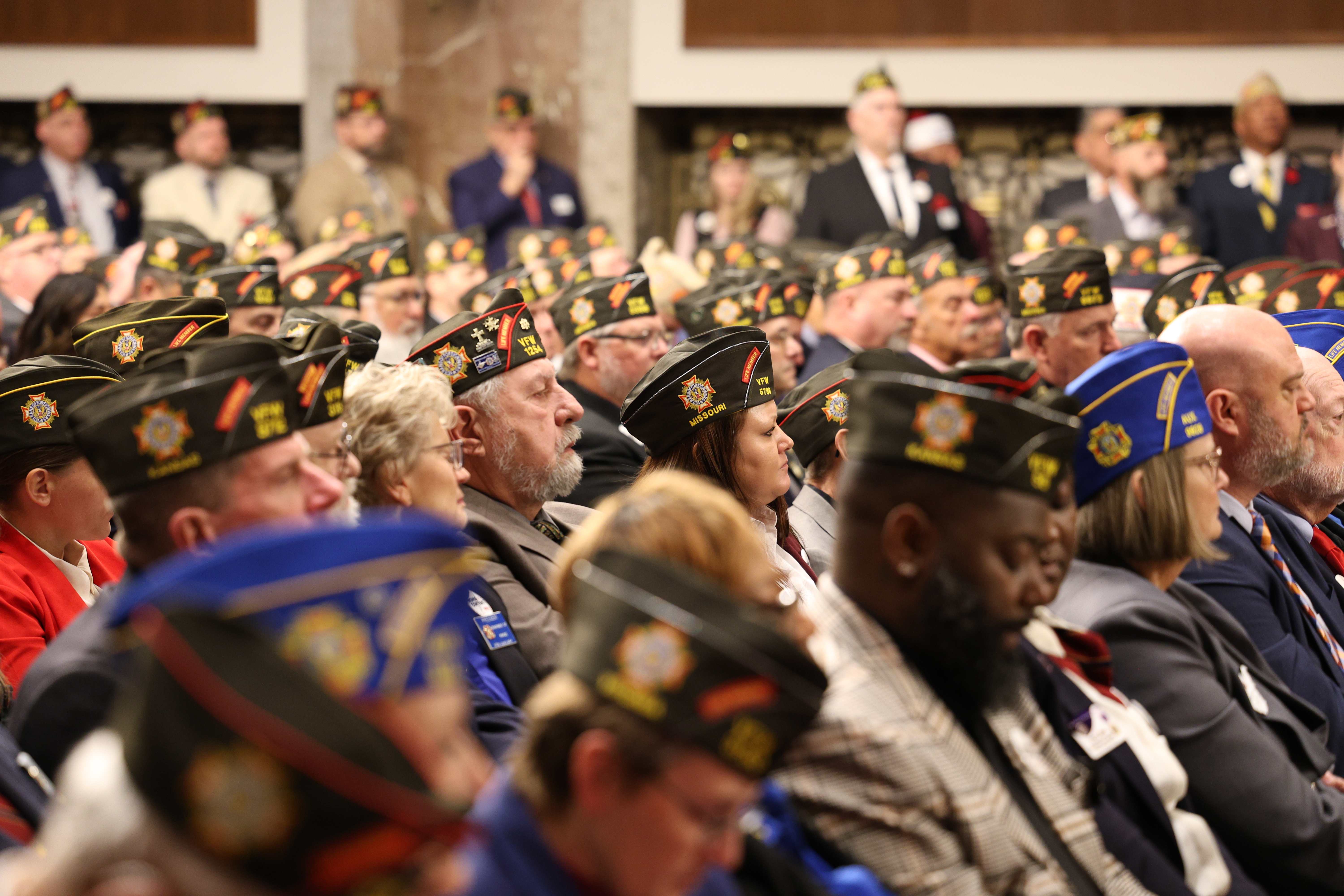 VFW members in garrison caps gathered at a formal event — representing veterans across eras and all branches of service