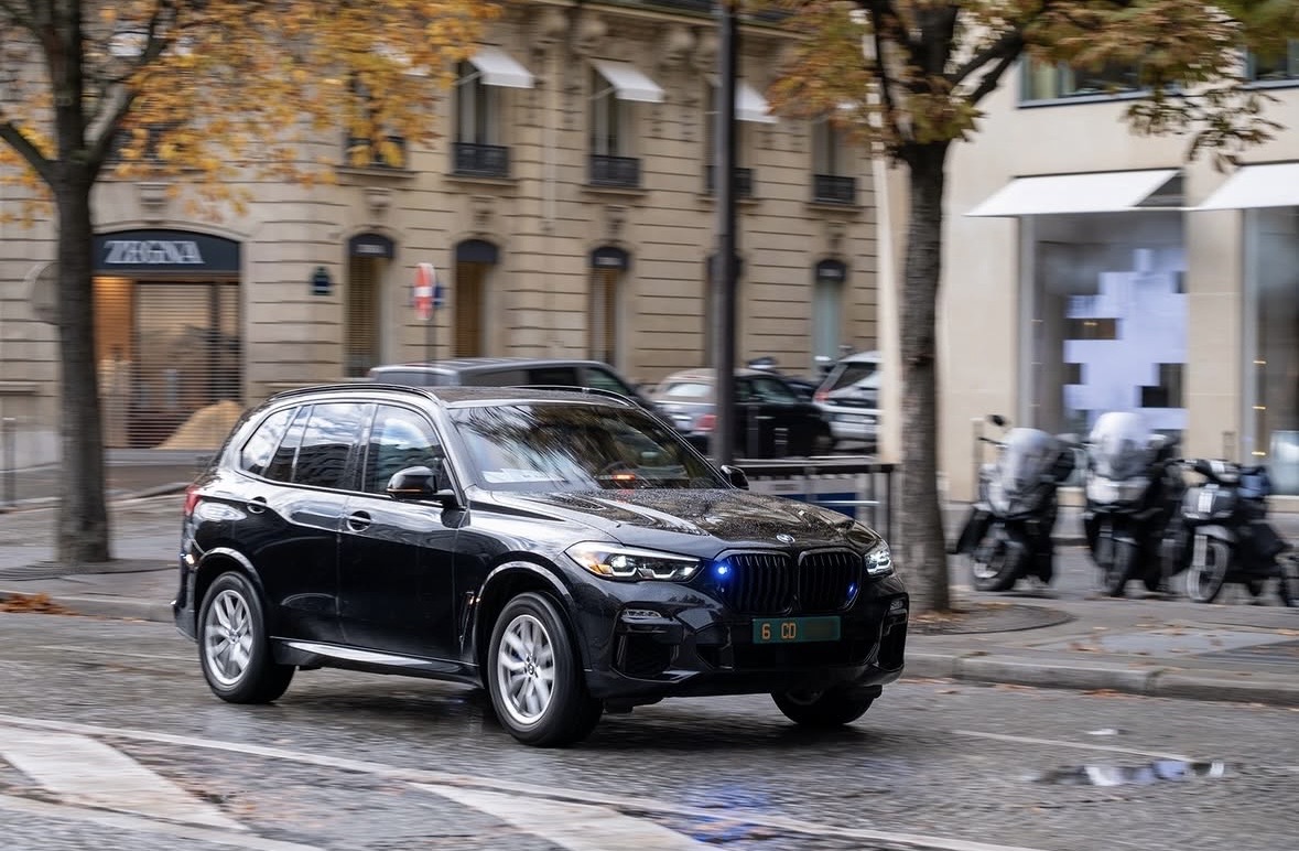 Plaque 6 CD — États-Unis, BMW X5 avec gyrophare, Paris Plaque diplomatique verte 6 CD sur un BMW X5 noir avec gyrophare bleu roulant à Paris sous la pluie — code 6 États-Unis