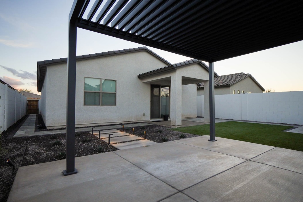 Attached dark louvered patio cover with view of home and turf yard