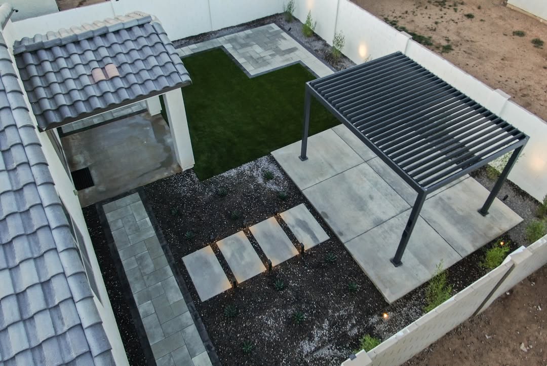 Aerial view of dark louvered pergola on concrete patio with paver walkway