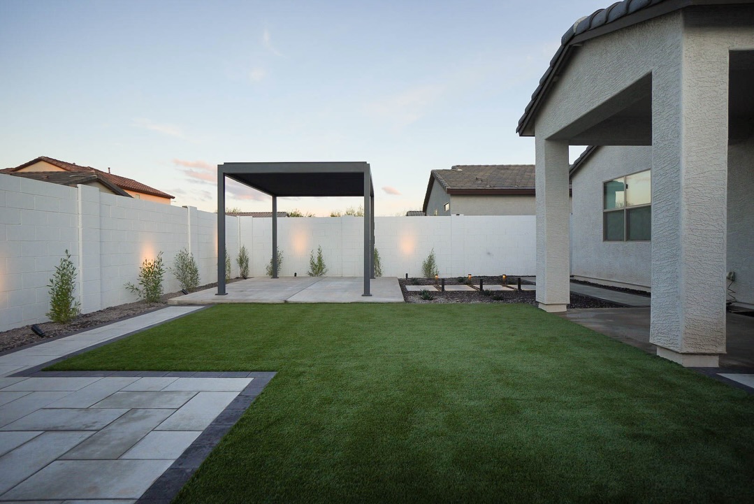 Freestanding dark solid-roof pergola beside artificial turf yard