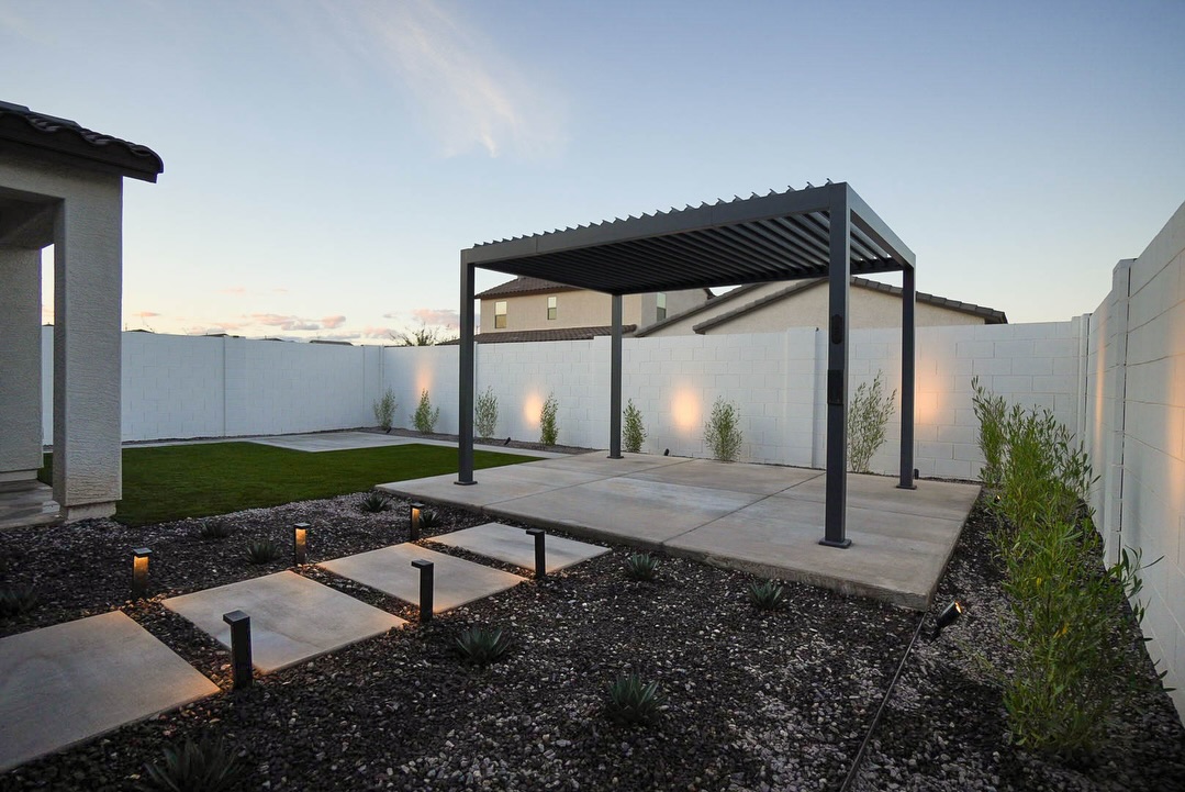 Dark louvered pergola on paver patio with desert landscaping at dusk