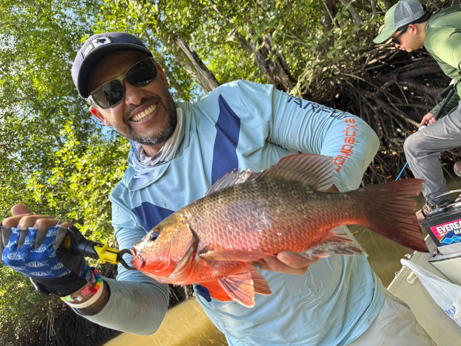 Pescador mostrando un pez rojo en el manglar