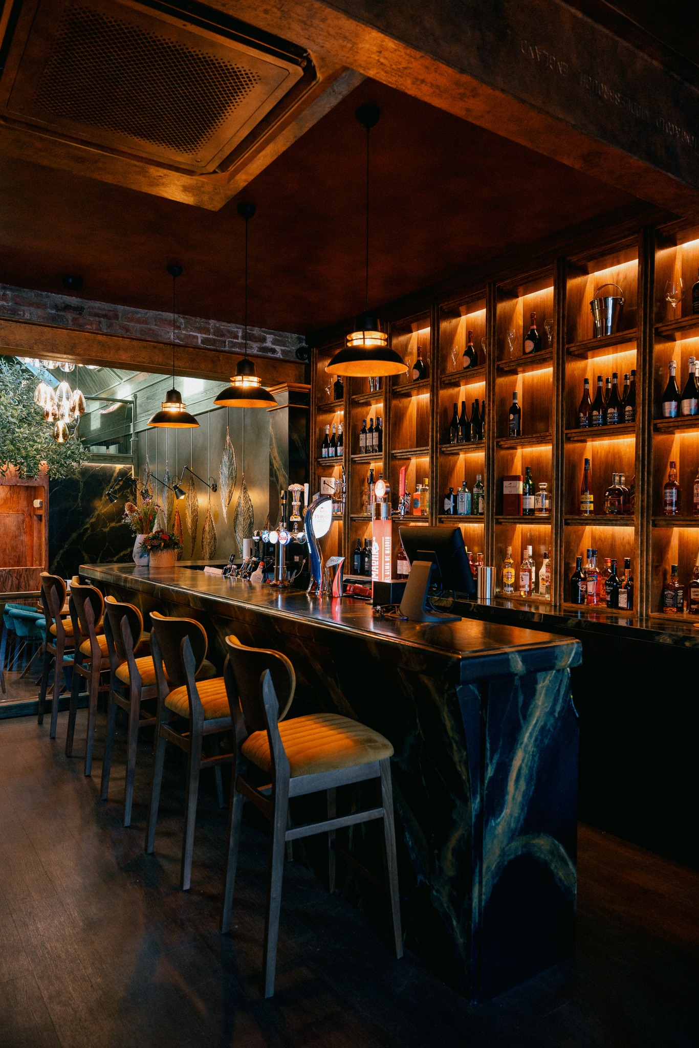 The elegant bar counter with backlit spirit shelves and marble finish