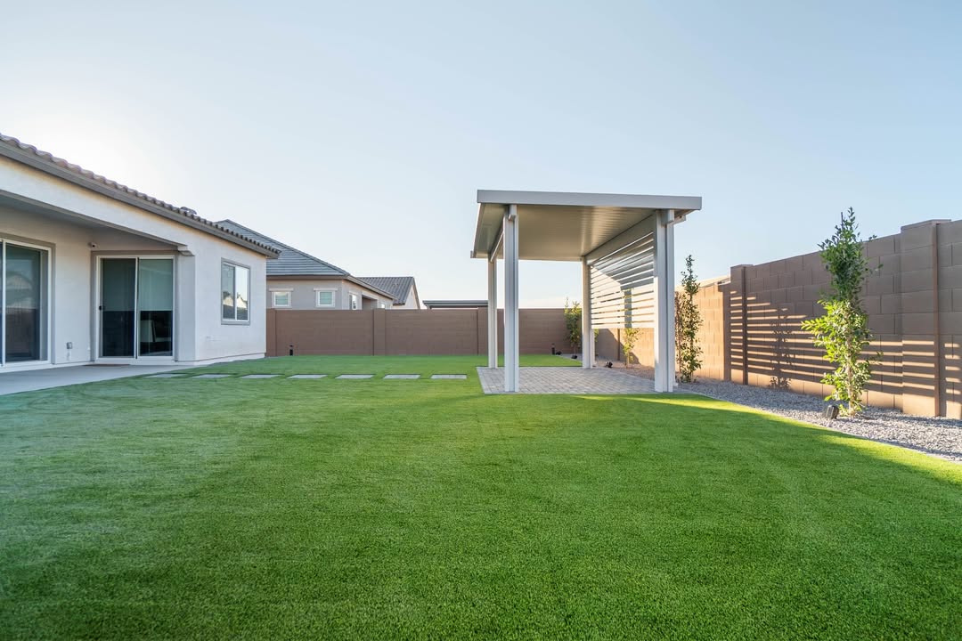 White solid-roof patio cover attached to home with turf yard