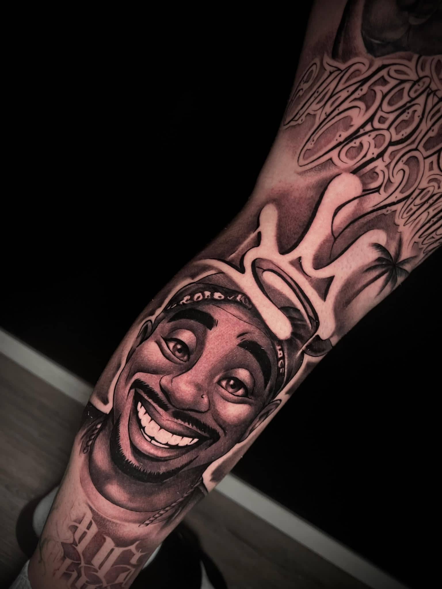 Black and Grey Tupac-Portrait mit Krone und Graffiti am Unterarm