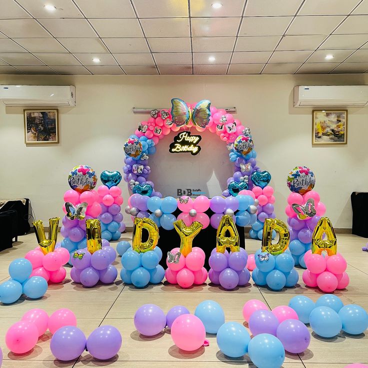 Butterfly theme birthday with pink, purple and blue balloons and Happy Birthday neon sign