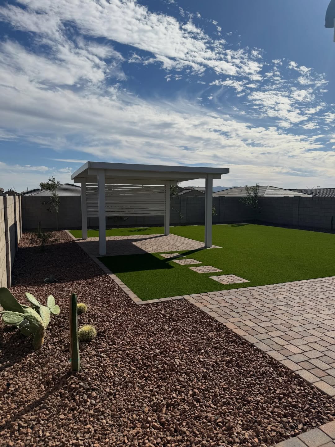 White patio cover with desert gravel landscaping and turf under blue sky