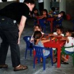 Betreuer mit Kindern an bunten Tischen