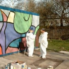 Zwei Maler in weißen Overalls arbeiten an der Graffiti-Wand