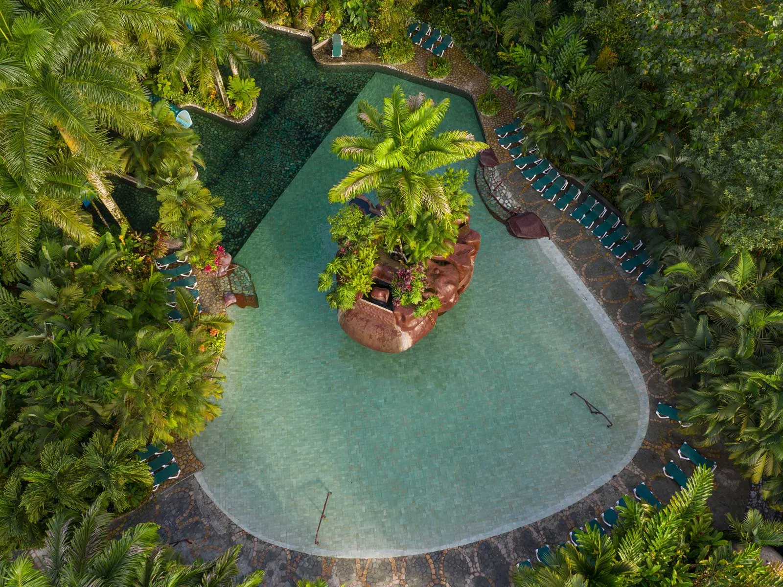 Aerial view of tropical resort pool surrounded by lush rainforest