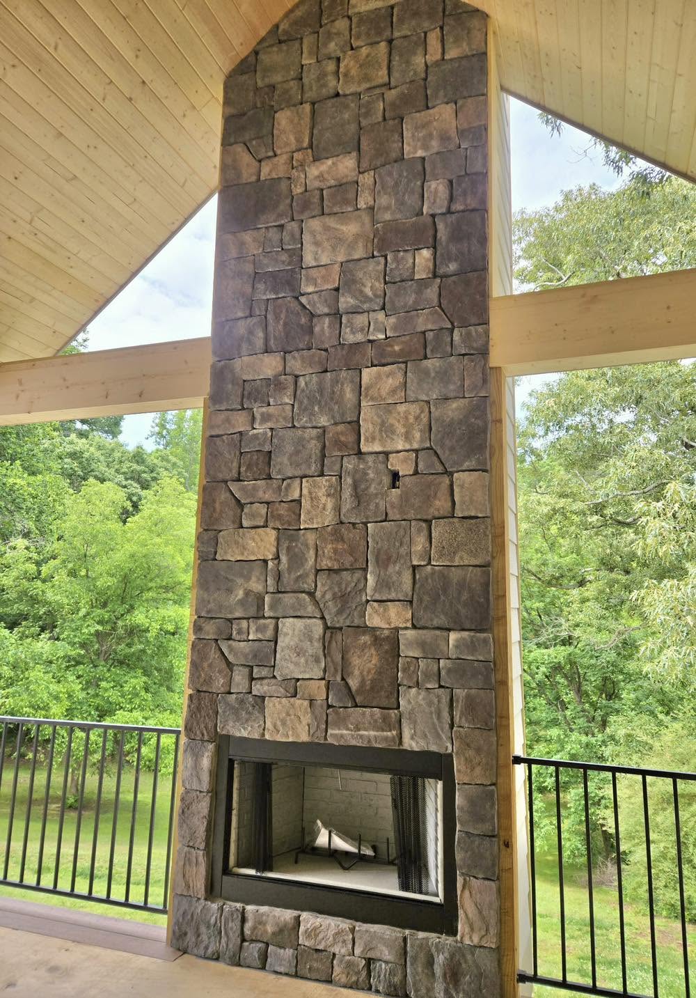 Vaulted covered-porch addition with a full-height stacked stone fireplace
