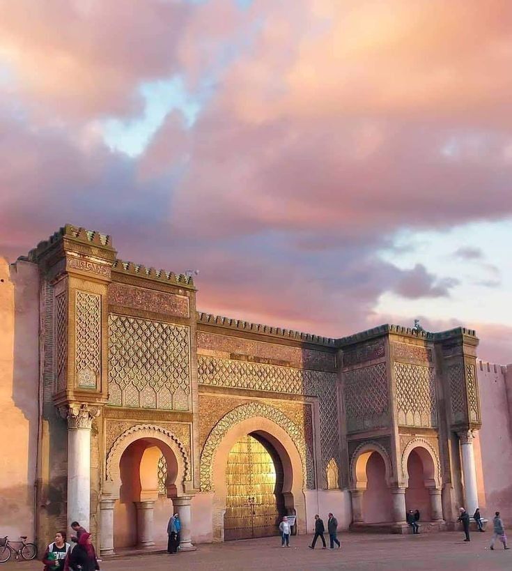 Bab Mansour gate in Meknes at sunset with dramatic pink and orange sky