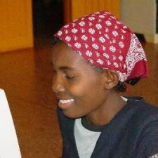 Jugendliche mit rotem Kopftuch lächelt konzentriert vor einem Computer