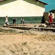 Arbeiter planieren Sandgrund neben einem Gebäude