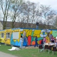 Gesamtansicht: mehrere Maler arbeiten an der Graffiti-Fassade