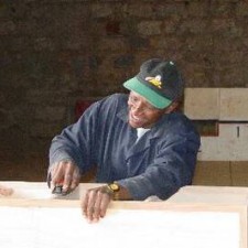 Tischler hobelt in der Lehrwerkstatt ein Holzbrett