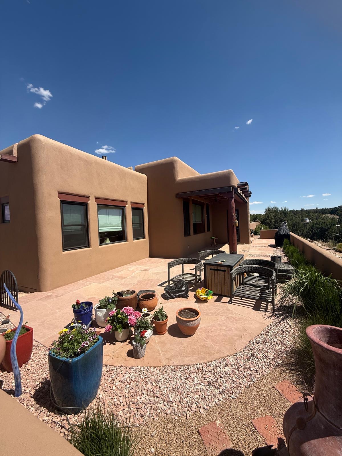 Back patio view of adobe home with smooth stucco and covered porch