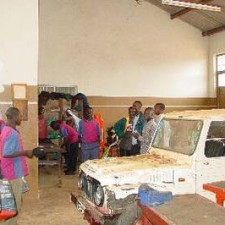 Schülergruppe inspiziert ein Fahrzeug in der KFZ-Werkstatt