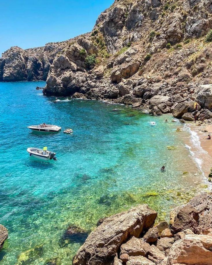 Crystal turquoise cove with dramatic rocky cliffs and fishing boats