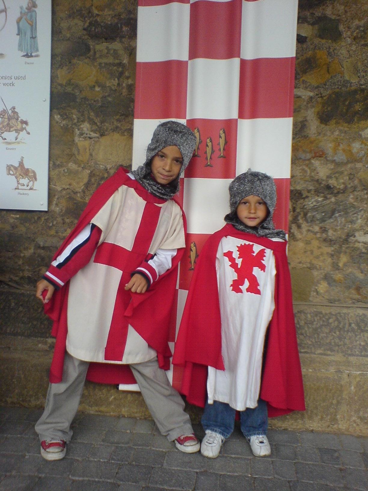 Two young boys dressed as medieval knights in red and white tabards and chainmail hoods