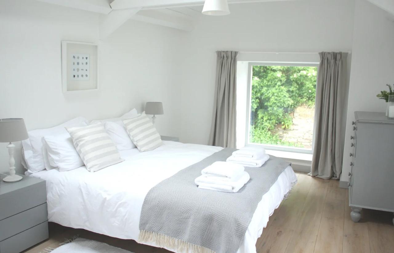Serene double bedroom with beamed ceiling, striped pillows, and garden window
