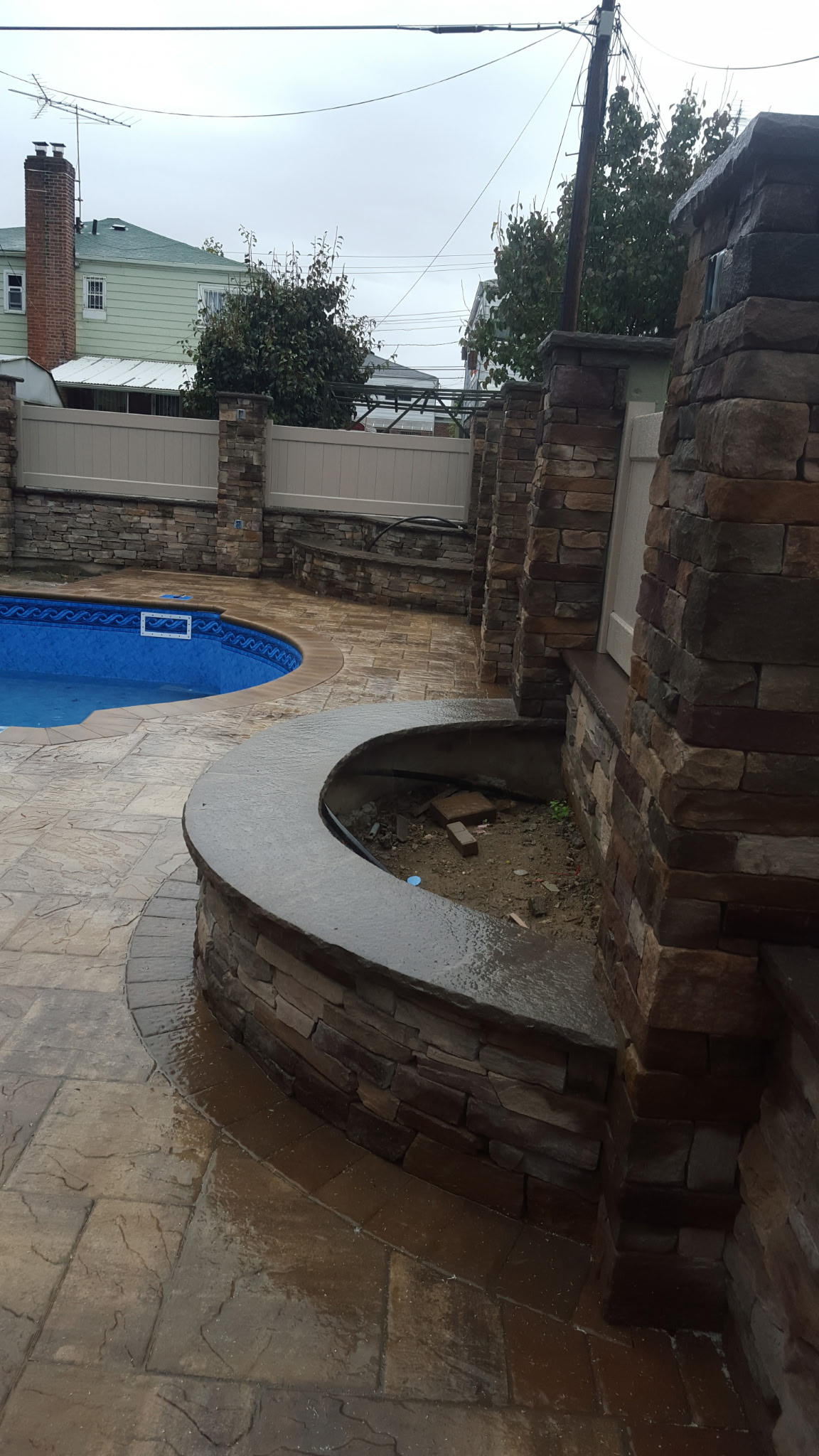 Curved stone planting bed built beside pool and stone patio
