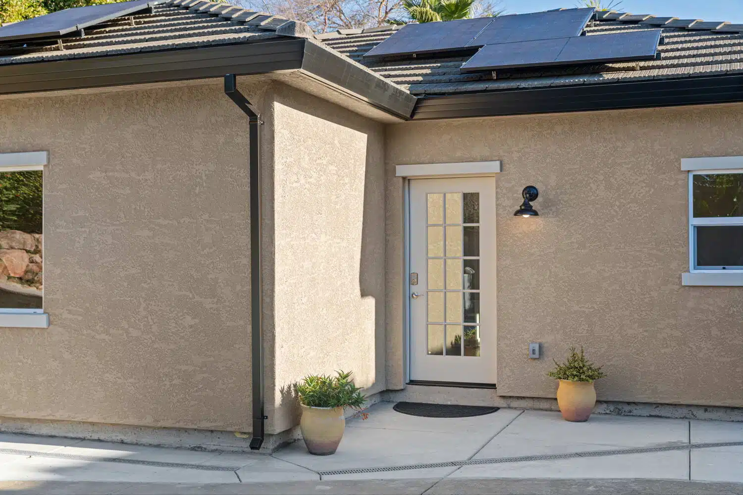 Close-up of ADU French door entry with potted plants and barn light sconce