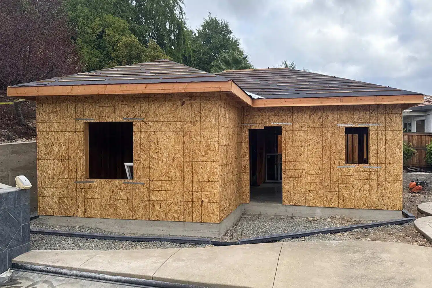 ADU during OSB framing construction phase with hip roof structure and open window rough openings