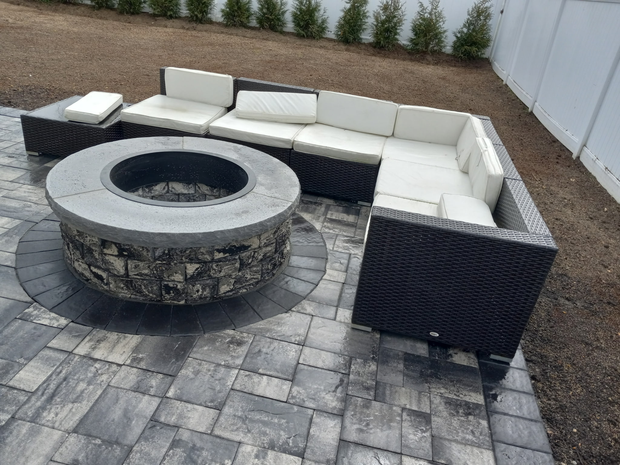 Modern paver patio with a round stone fire pit and sectional seating