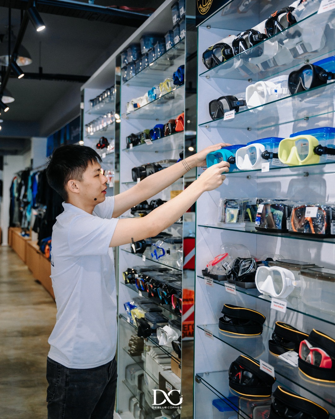 De Blue Corner staff arranging dive masks on display shelf