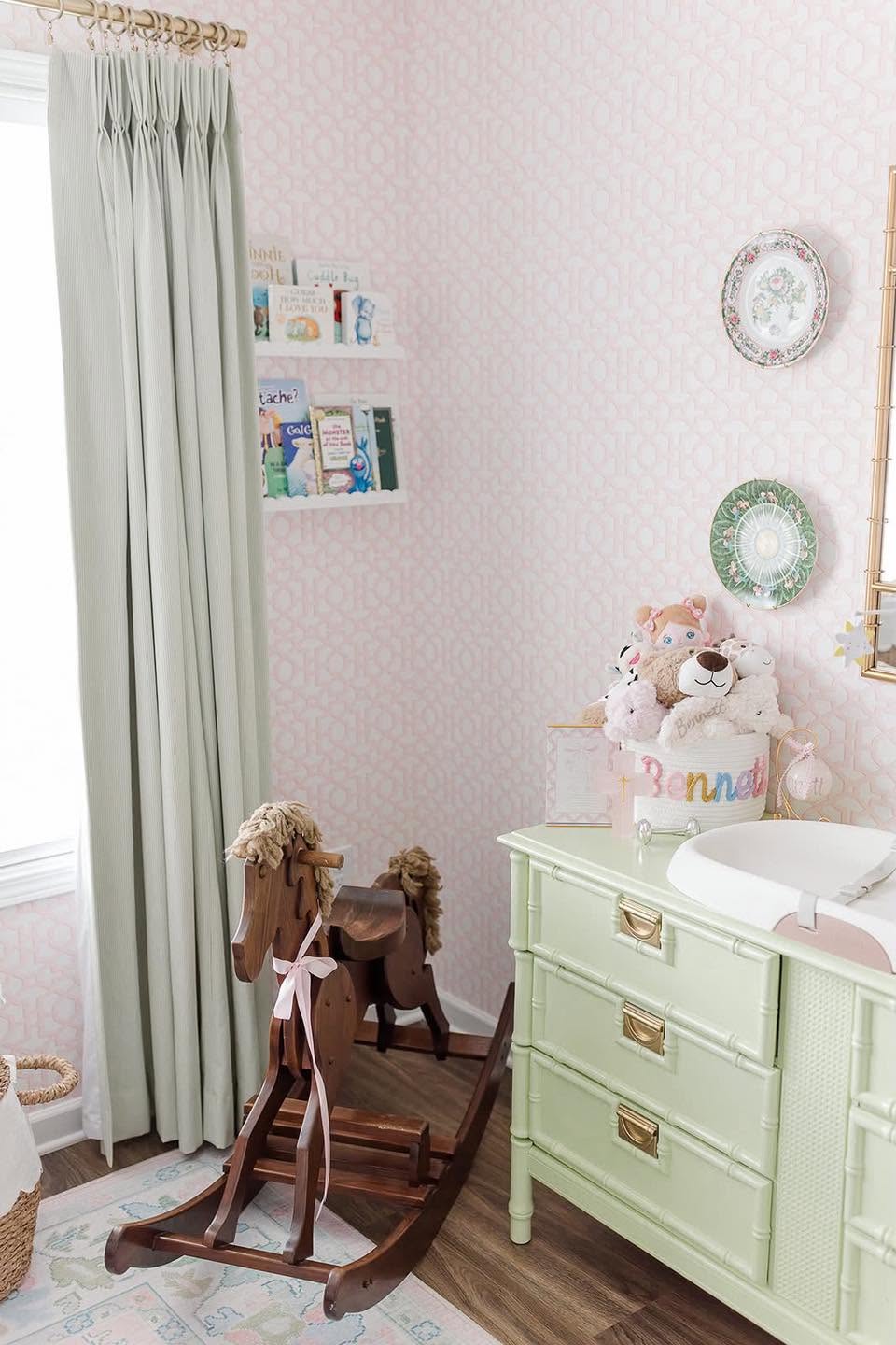 Nursery with pink trellis wallpaper and coordinated striped drapery