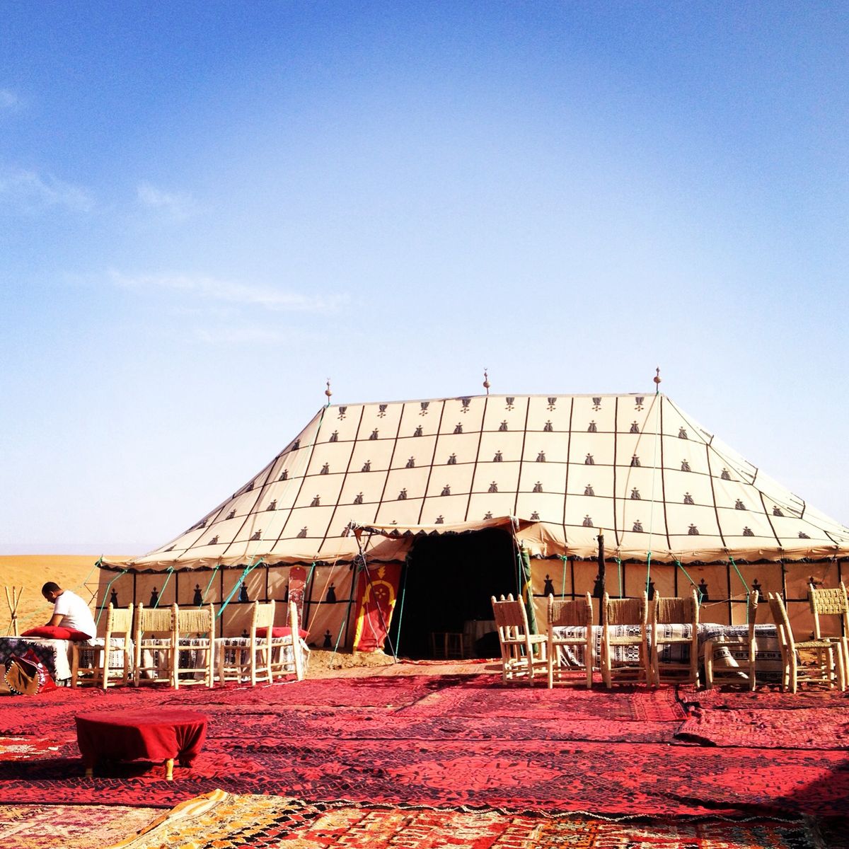 Large traditional Bedouin tent in desert with cream canvas and red carpeting