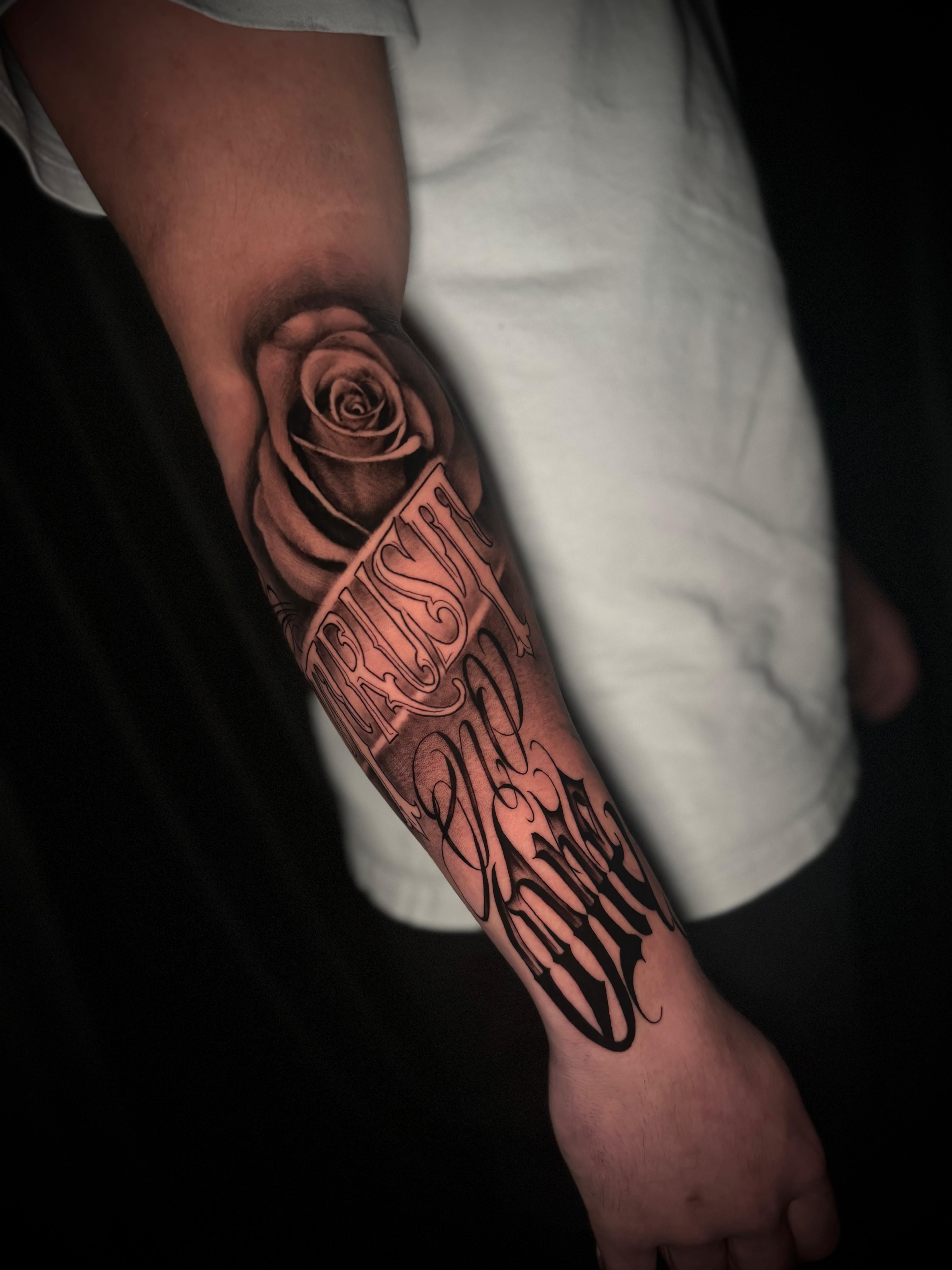 Lettering Trust No One Chicano-Schrift mit Rose am Unterarm frisch gestochen