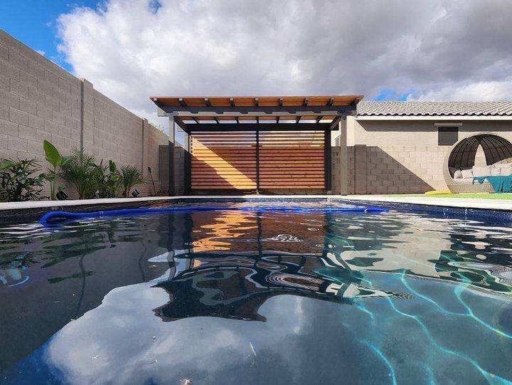 Slatted privacy screen and patio cover beside a dark backyard pool
