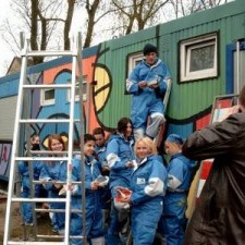 Gruppe in blauen Overalls auf Leiter, Fotograf im Vordergrund