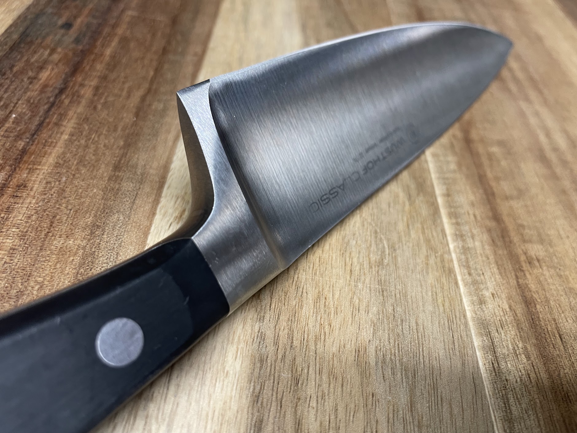 Close-up of a freshly sharpened Wusthof Classic chef knife blade on a wooden cutting board