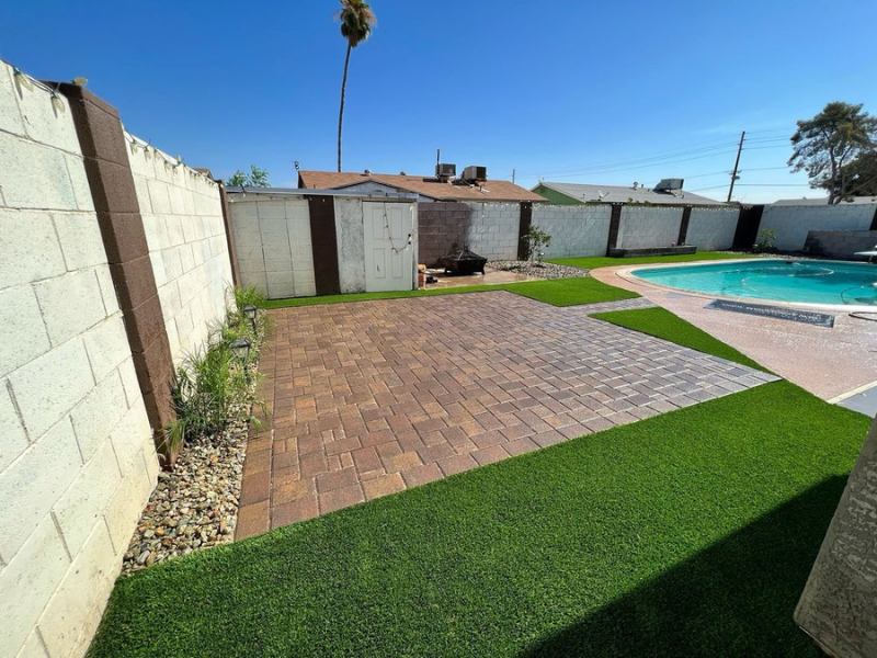 Turf backyard with paver patio, pool, and storage shed