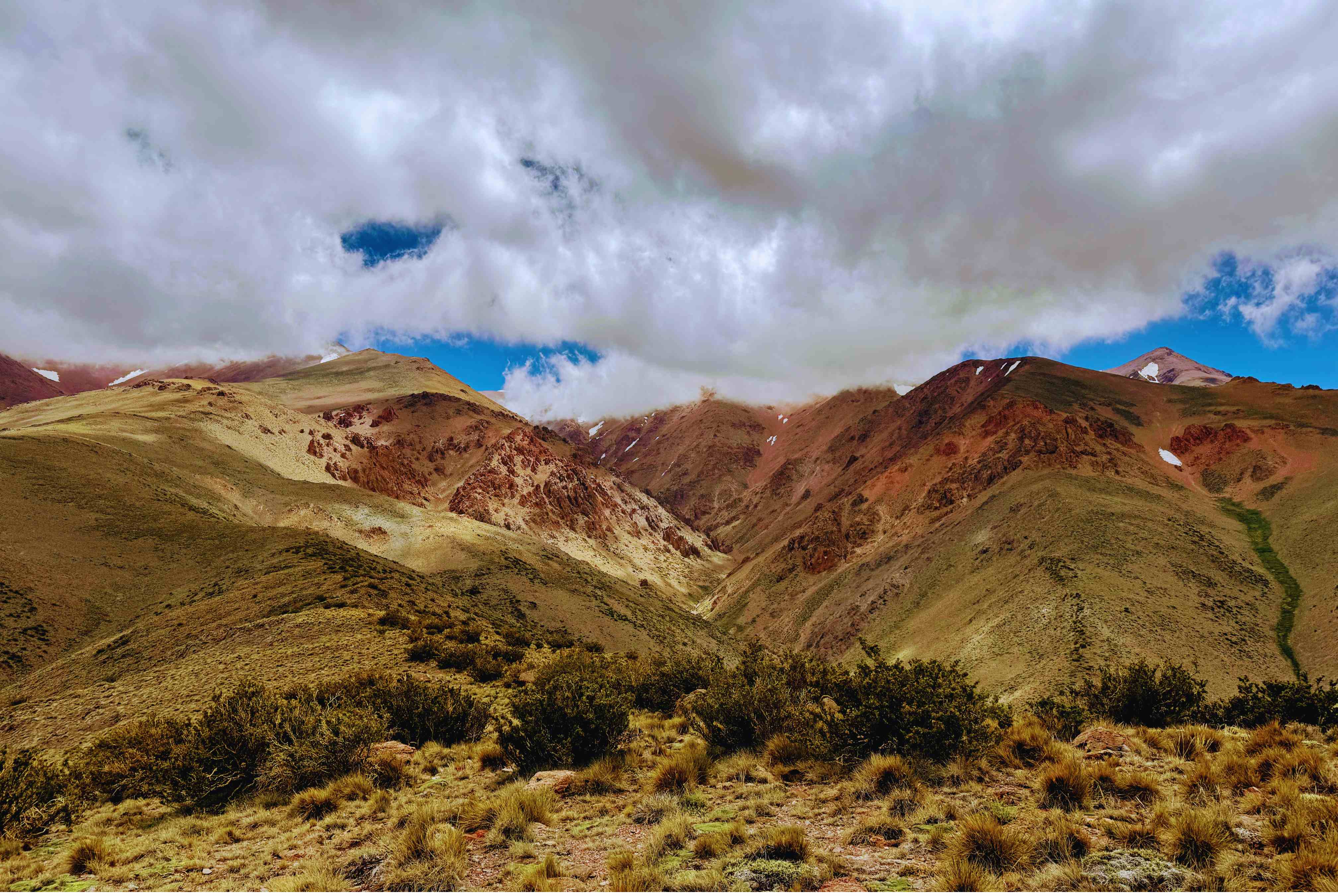 Cordones montañosos con tonos ocres y verdes bajo cielo nublado