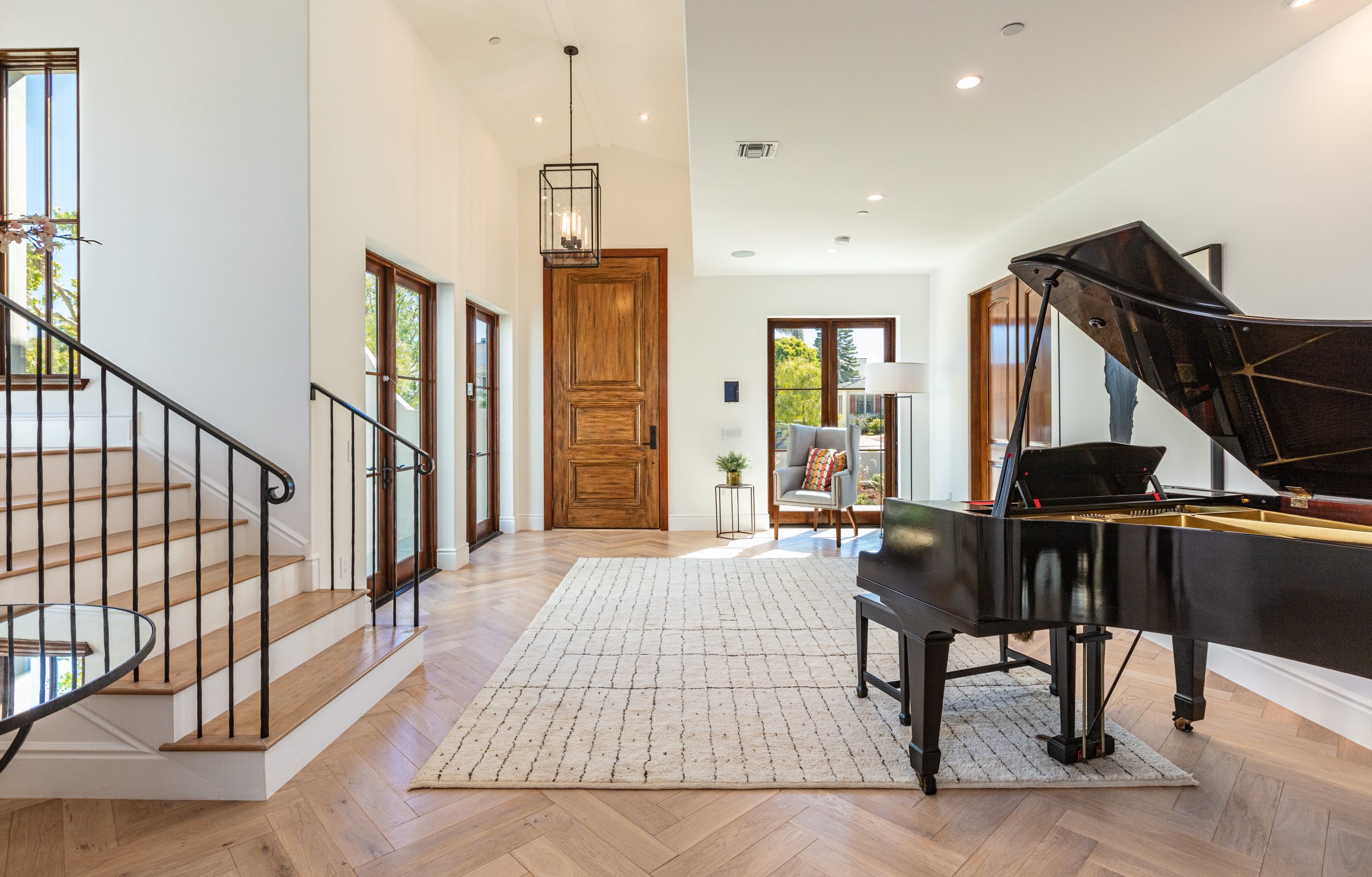 Stunning entrance foyer with grand piano, featuring high ceilings and elegant wooden staircase