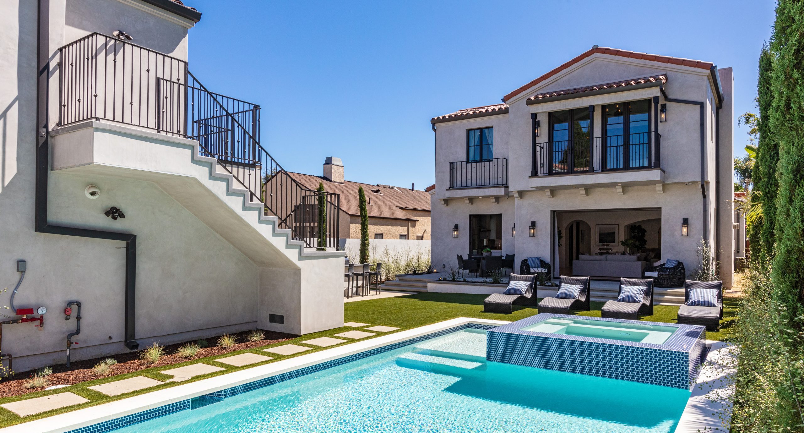 Beautiful Mediterranean-style backyard with modern pool and spa, featuring comfortable lounging areas