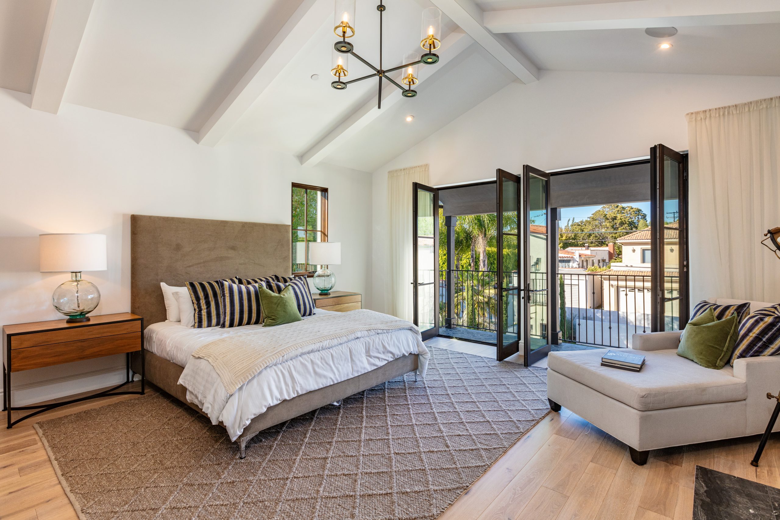 Luxurious master bedroom with vaulted ceilings and French doors leading to a private balcony