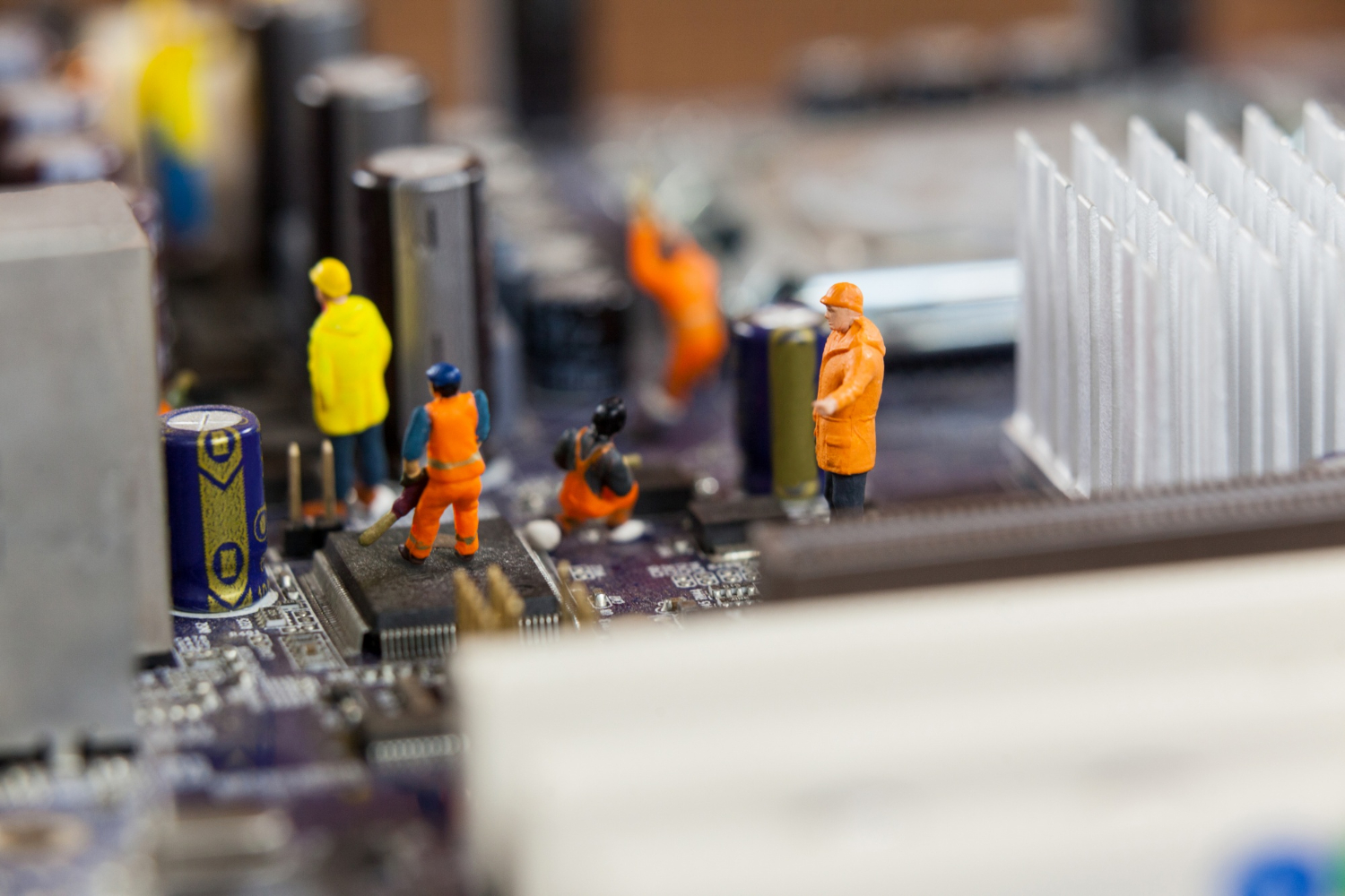 Miniature technician figurines working on a circuit board representing precision electronics repair