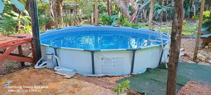 Piscina redonda bajo la sombra de los árboles, junto a una terraza de madera