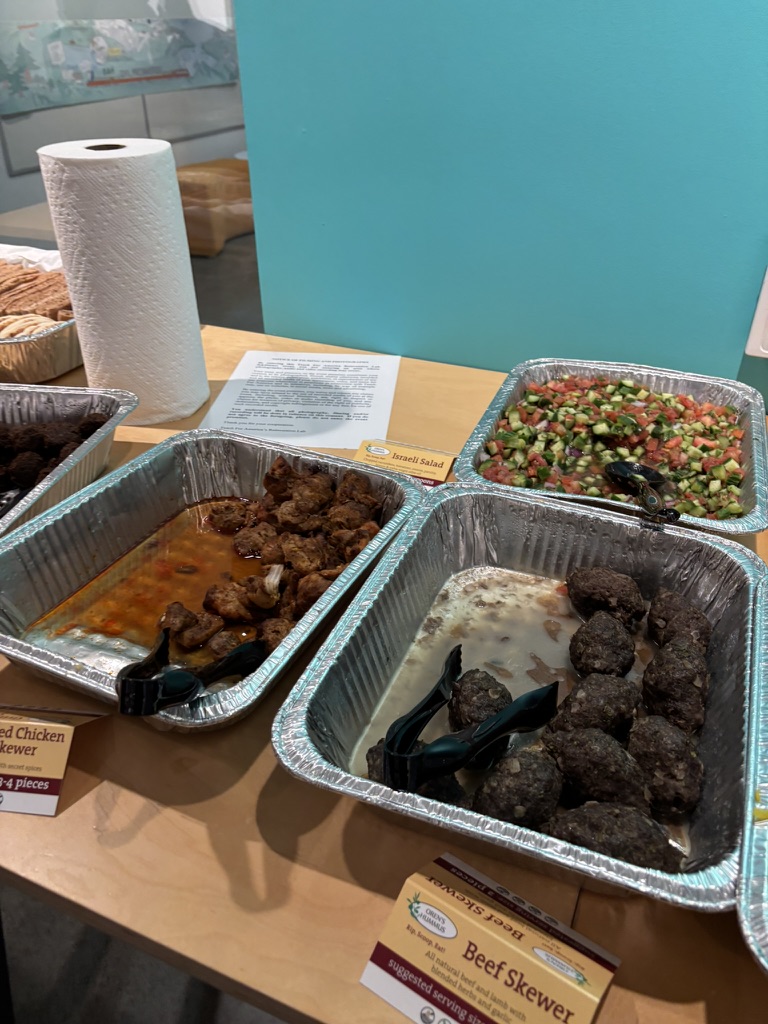 Mediterranean food spread including chicken, meatballs, salad, and Israeli salad
