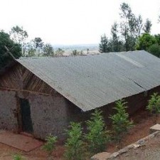 Altes Lehmgebäude mit Wellblechdach auf roter Erde