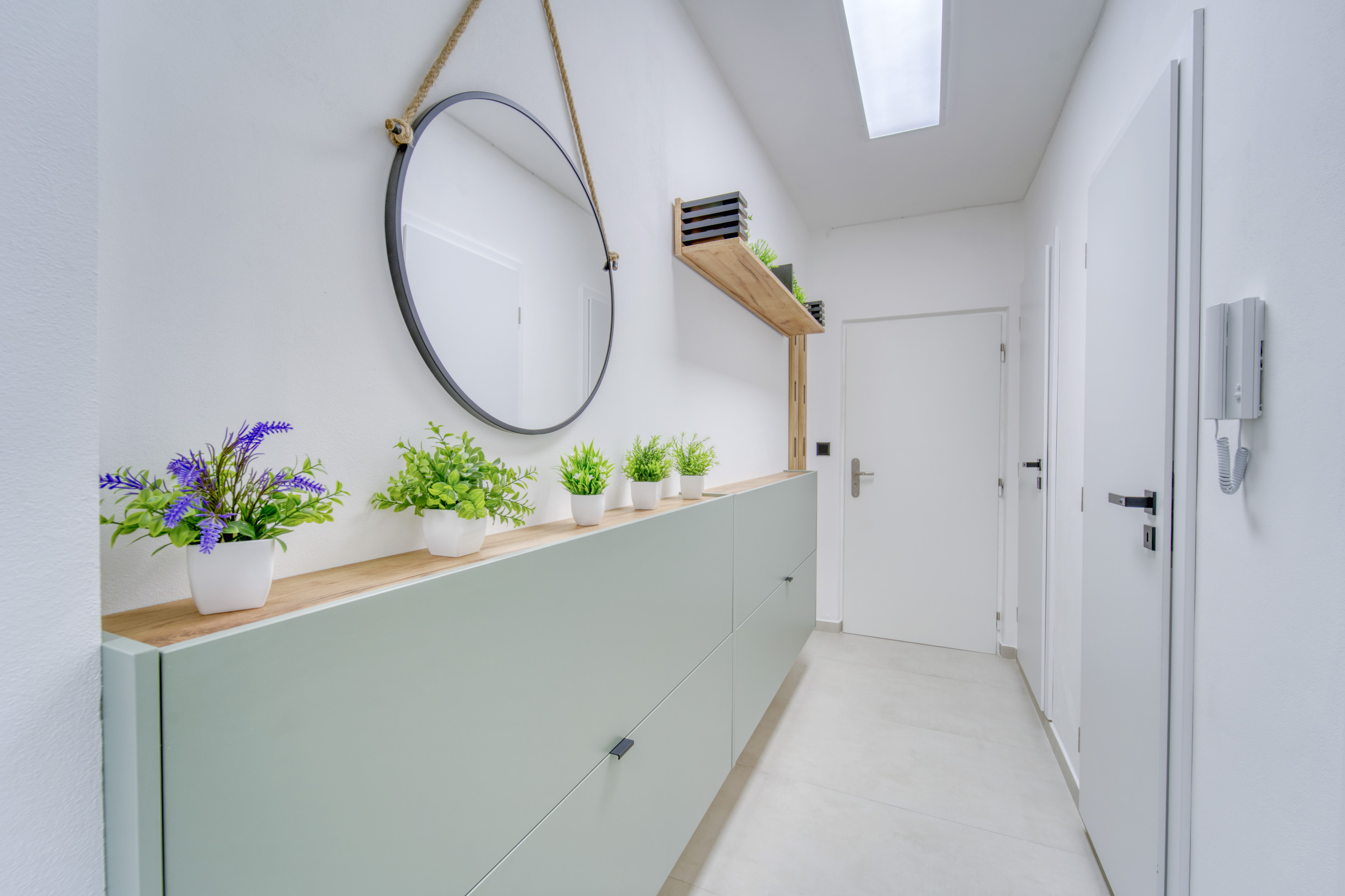 Bright hallway with plants and a round mirror