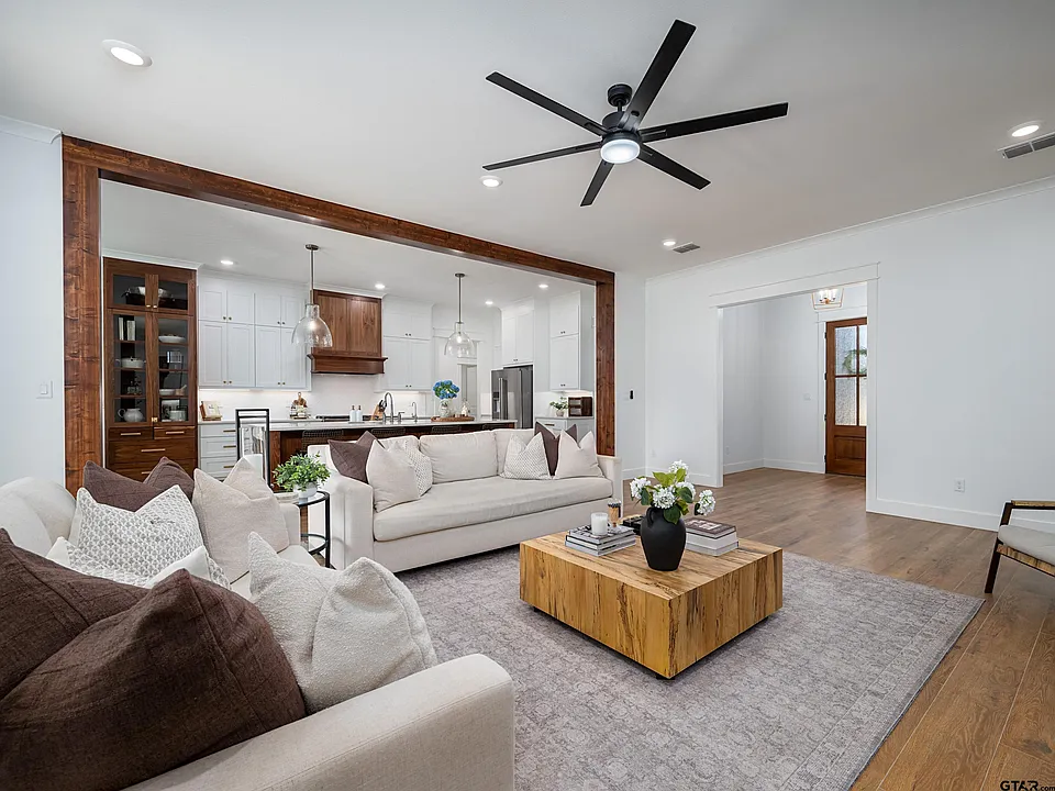 Open living room with wood beam surround and kitchen view
