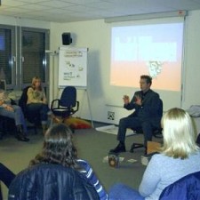 Vortrag mit Beamer vor sitzender Gruppe