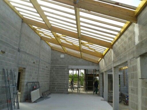 Chantier de construction avec charpente en bois posée sur murs en blocs de béton